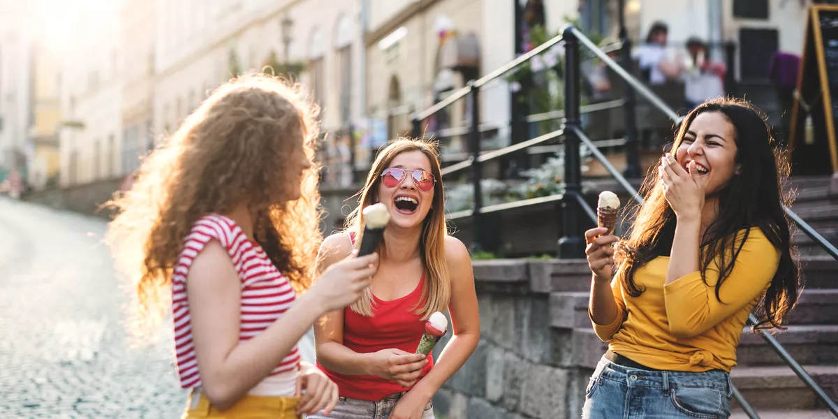 Three Cheerful Female Teenager Friends With Ice Cream Standing On The Street, Laughing 1007285794